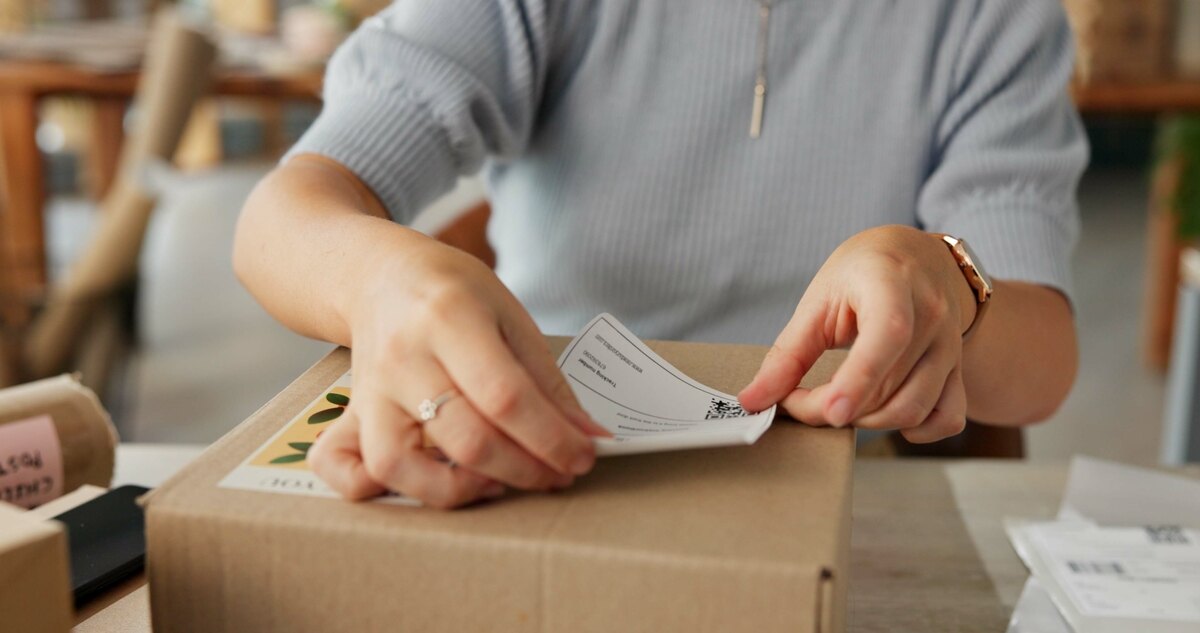 Person labeling a cardboard box in a cozy room, showing focus and productivity.